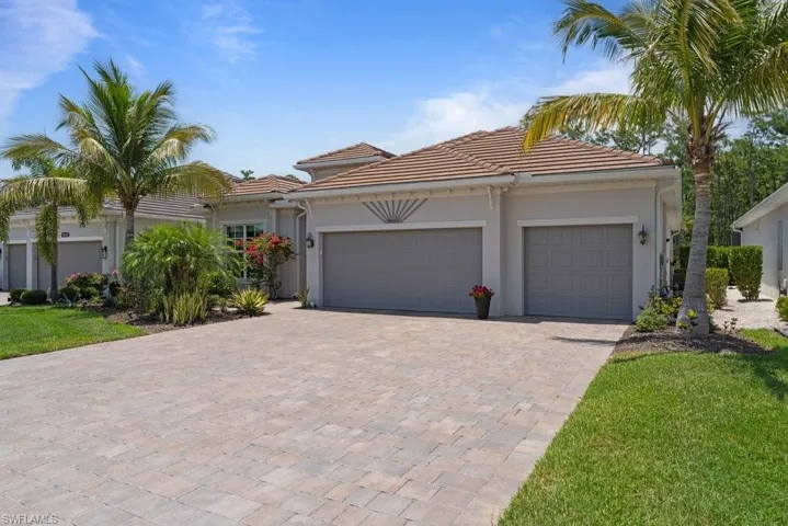 View of front of home featuring decorative driveway, a tile roof, a garage, stucco siding, and a front lawn