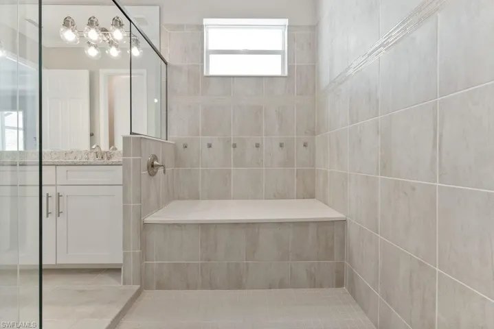 Bathroom featuring tile patterned floors, a tile shower, vanity, and a chandelier