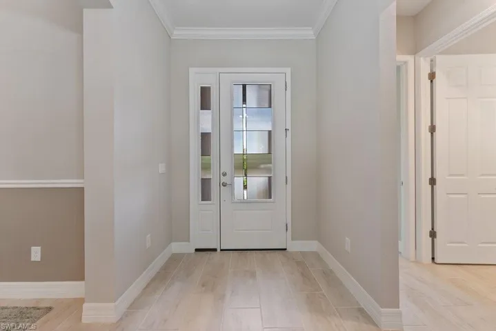 Foyer featuring crown molding, baseboards, and light wood-style flooring