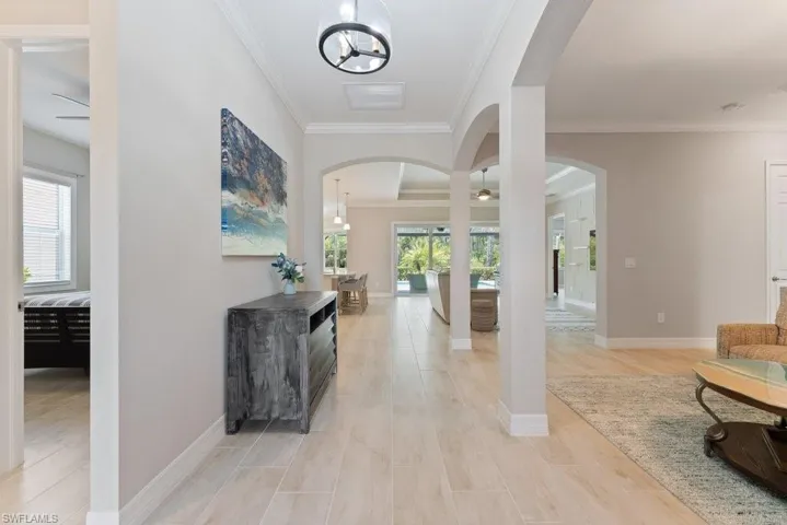 Foyer entrance with ornamental molding, arched walkways, plenty of natural light, baseboards, and a ceiling fan