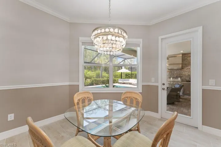 Dining room featuring a chandelier, tile patterned flooring, and crown molding