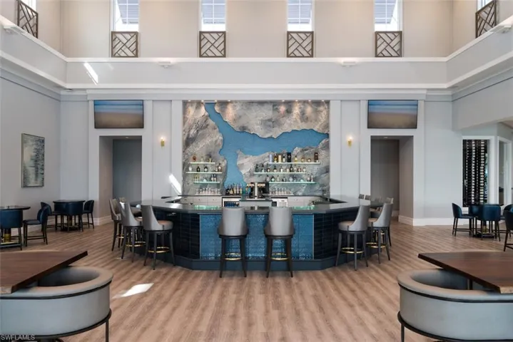 Indoor wet bar with a high ceiling, wood finished floors, and baseboards