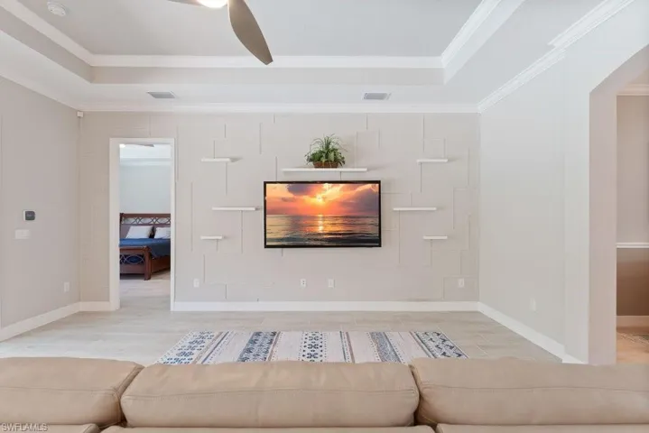 Living room featuring a tray ceiling, crown molding, wood finished floors, and baseboards