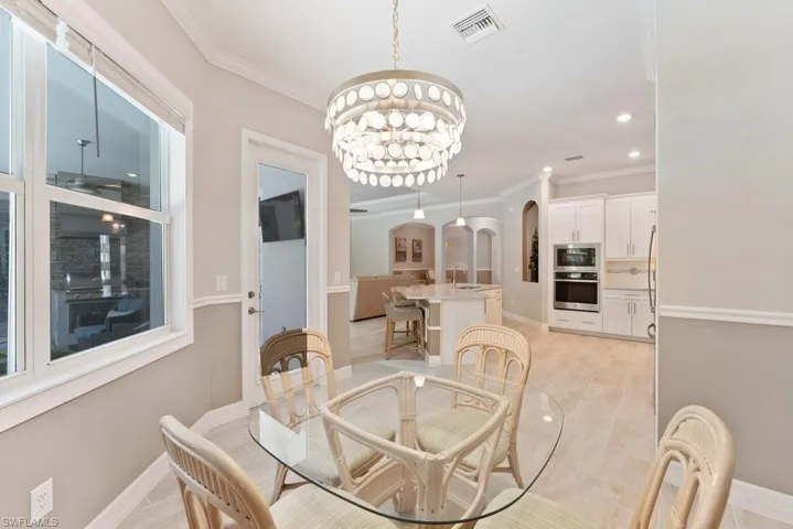 Dining space featuring arched walkways, a chandelier, crown molding, baseboards, and recessed lighting
