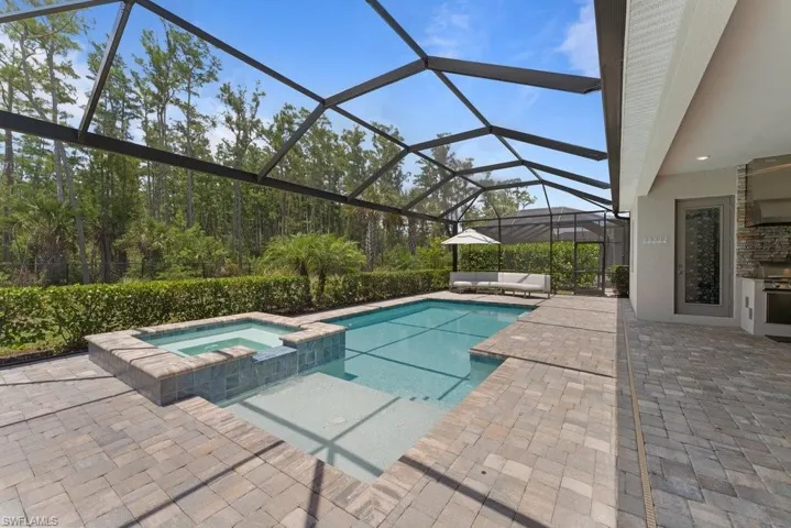 View of swimming pool featuring a patio, a lanai, a pool with connected hot tub, and outdoor lounge area