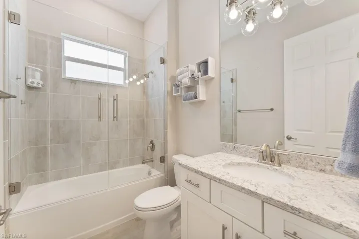 Bathroom with vanity, toilet, and shower / bath combination with glass door