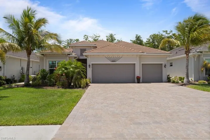 Mediterranean / spanish-style home featuring decorative driveway, a garage, a front yard, stucco siding, and a tiled roof