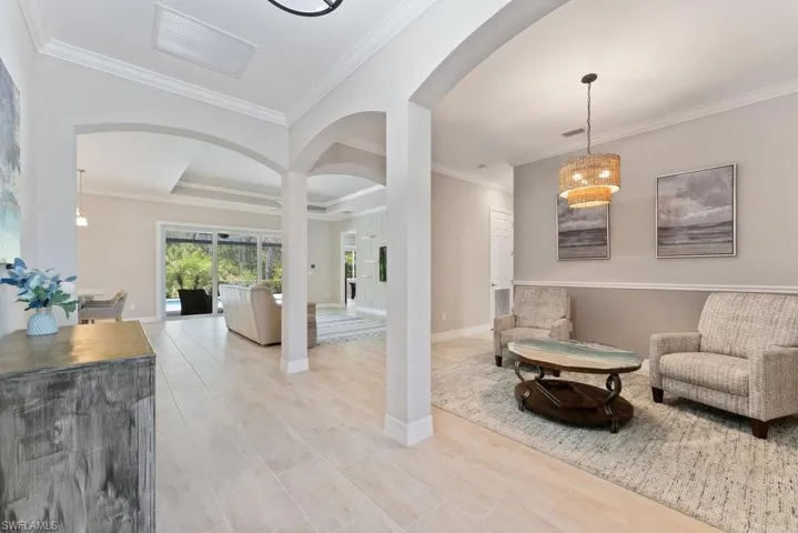 Living area featuring arched walkways, ornamental molding, and baseboards