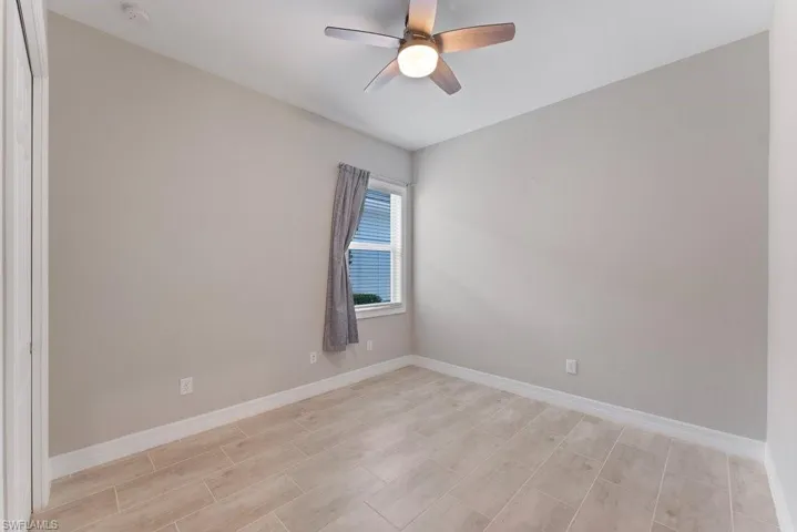 Unfurnished room with baseboards, a smoke detector, a ceiling fan, and light wood-style flooring
