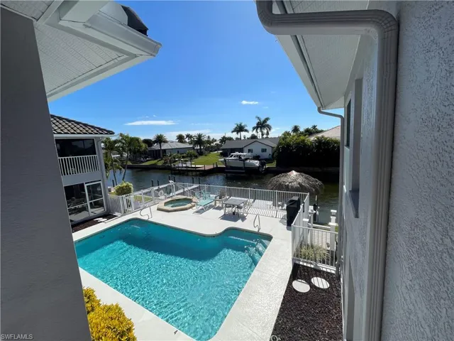 View of pool with an in-ground hot tub, patio surround, and a water view