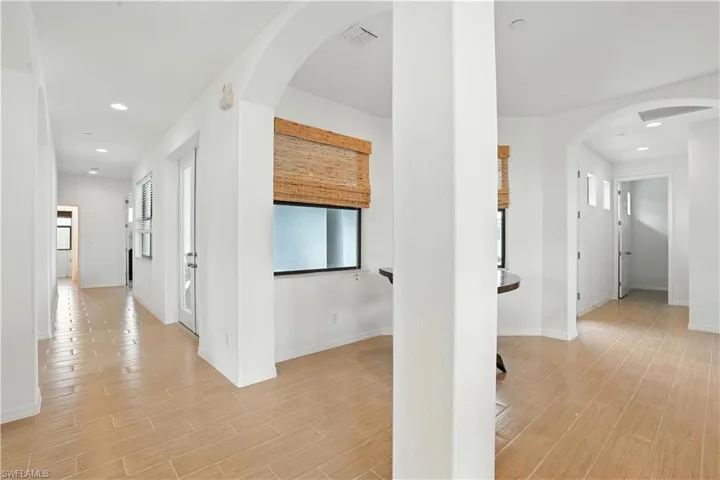 Expansive hallway featuring wood-finish flooring, recessed lighting, and arched doorways