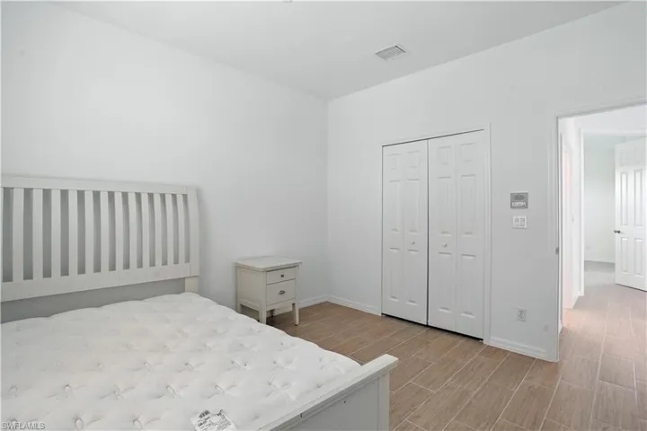 Spacious room featuring wood-finish flooring, white walls, and a ceiling-mounted air vent