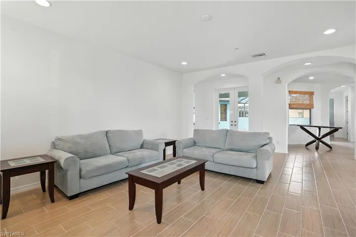 Spacious living area featuring light wood-finish flooring, recessed lighting, and white walls