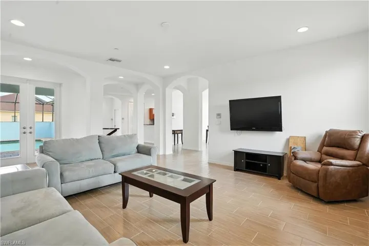 Open-concept living space with wood-finish flooring, recessed lighting, and white walls