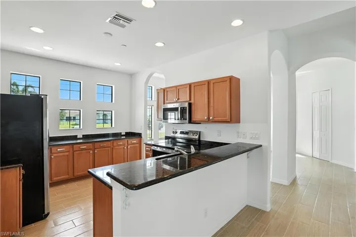Kitchen featuring wood-finish flooring, dark granite countertops, and wood-tone cabinetry
