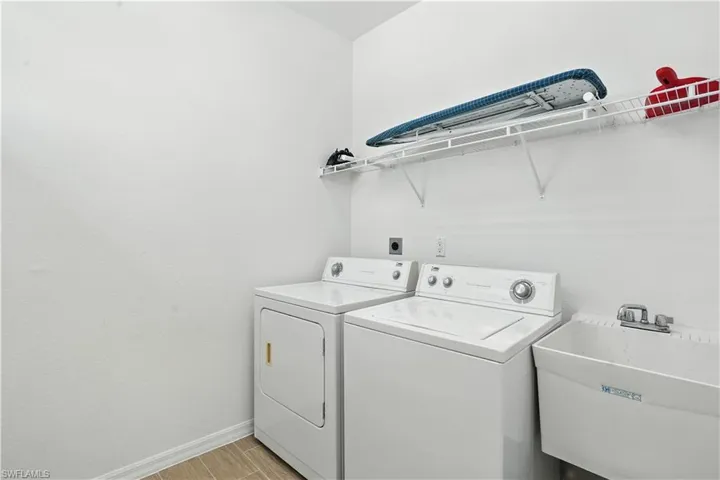 Dedicated utility room featuring a laundry sink, wire shelving, and wood-finish tile flooring