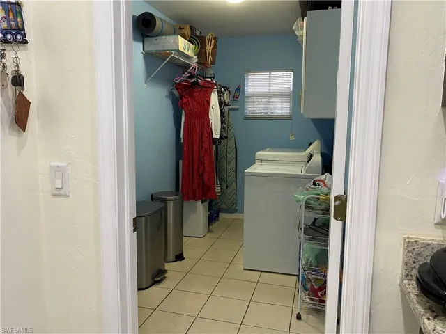 Washroom featuring laundry area, light tile patterned flooring, and washer and clothes dryer