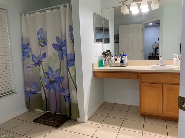 Full bathroom featuring tile patterned floors, baseboards, a shower with shower curtain, and vanity