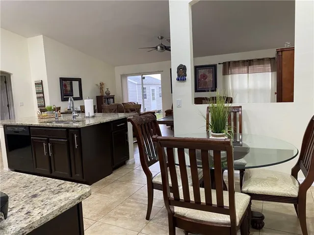 Dining room with light tile patterned floors, ceiling fan, and vaulted ceiling