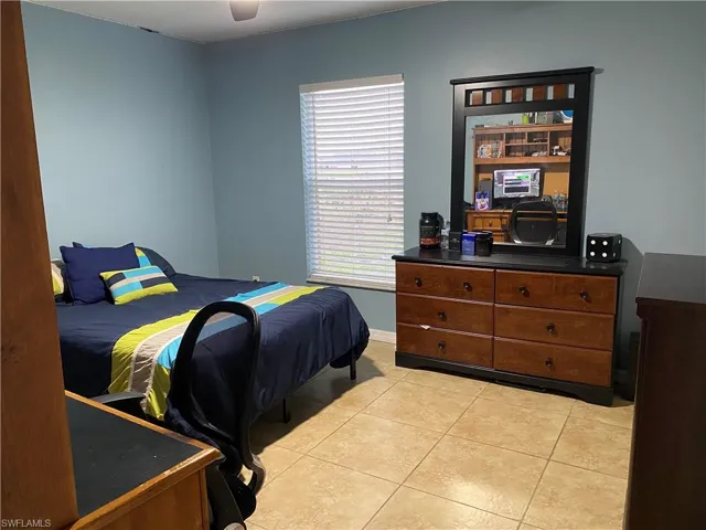 Bedroom featuring baseboards, light tile patterned flooring, and a ceiling fan