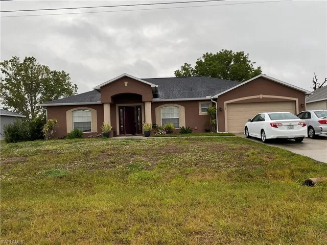 View of front of property featuring concrete driveway, a garage, a front yard, and stucco siding