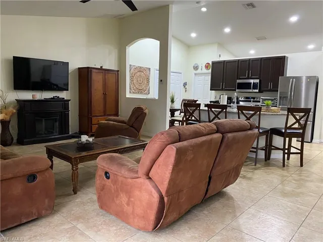 Living area featuring visible vents, high vaulted ceiling, recessed lighting, arched walkways, and a fireplace