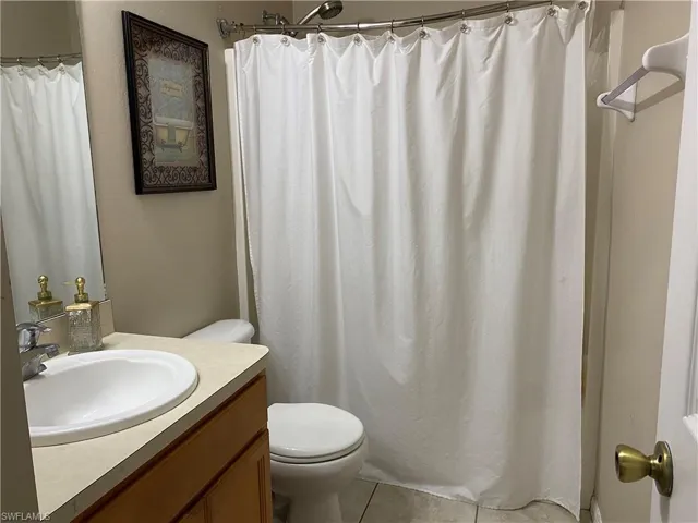 Full bathroom featuring tile patterned floors, curtained shower, toilet, and vanity