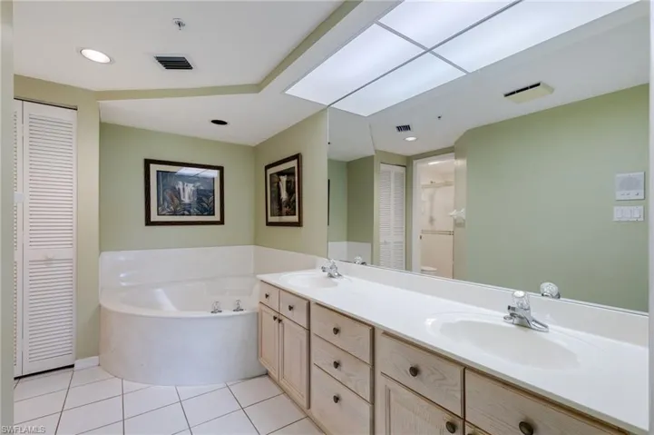 Bathroom with a closet, light tile patterned flooring, double vanity, a bath, and recessed lighting