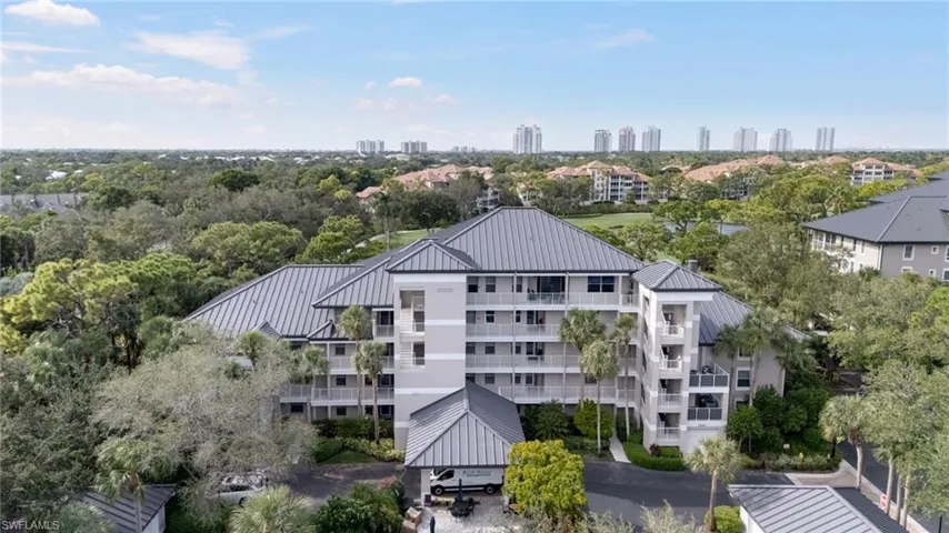 Drone / aerial view of a tree filled landscape and apartment complex / building
