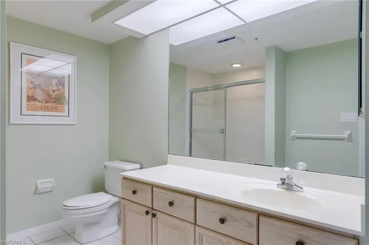 Bathroom with light tile patterned floors, vanity, and a shower stall