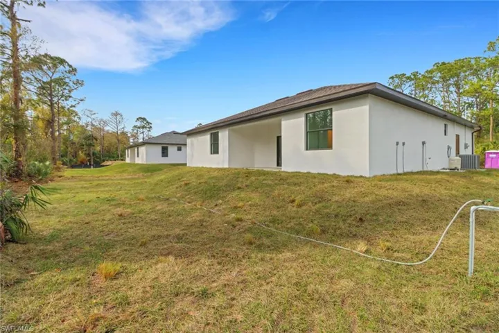 Rear view of property featuring central AC and a yard