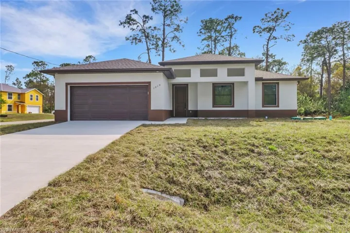 View of front of property featuring a garage and a front yard