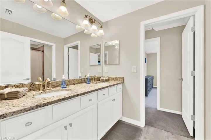 Bathroom featuring dual sinks, tile floors, and large vanity