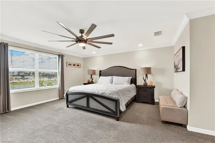 Bedroom with ornamental molding, carpet floors, and ceiling fan