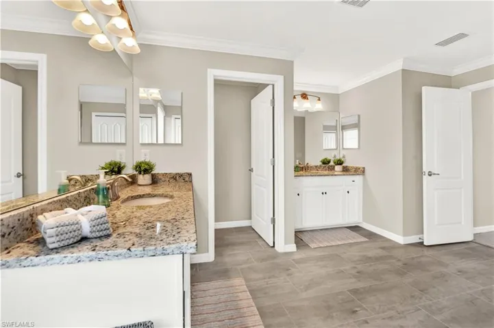 Bathroom featuring a notable chandelier, tile flooring, ornamental molding, and vanity