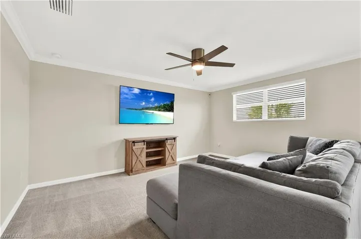 Carpeted living room featuring crown molding and ceiling fan