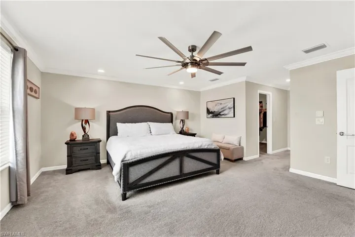 Carpeted bedroom with ceiling fan, a closet, crown molding, and a spacious closet