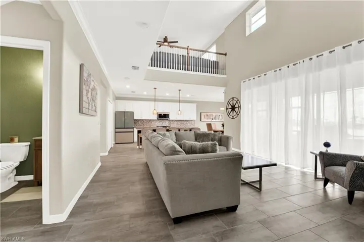 Living room with a high ceiling, tile flooring, ornamental molding, and ceiling fan