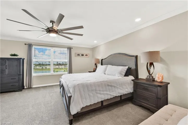 Carpeted bedroom with ceiling fan and crown molding