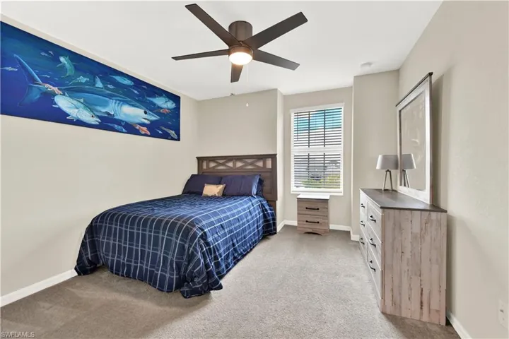 Carpeted bedroom featuring ceiling fan