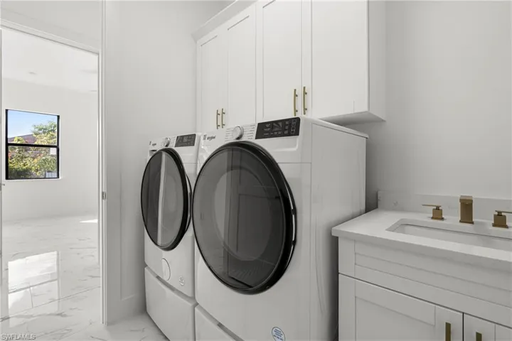 Laundry room featuring washer and clothes dryer, sink, and cabinets