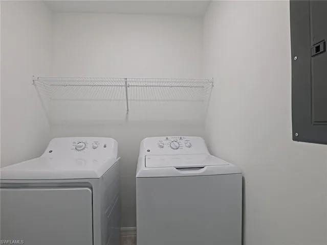 Laundry area featuring electric panel and washer and clothes dryer
