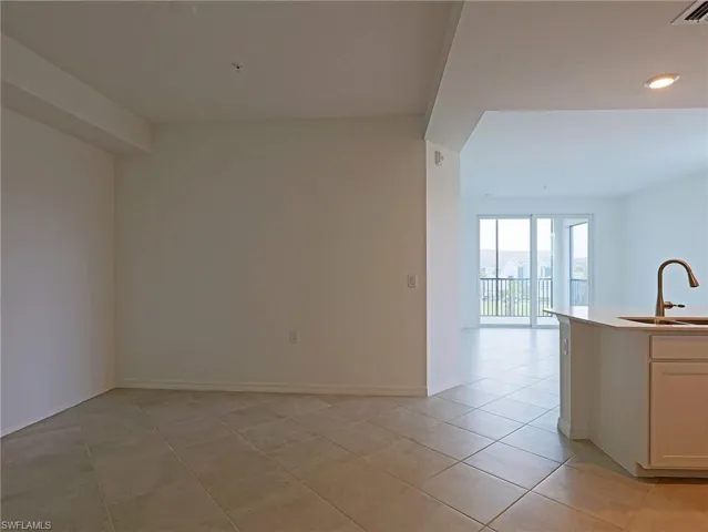 Kitchen with light tile patterned floors, white cabinetry, and light stone counters