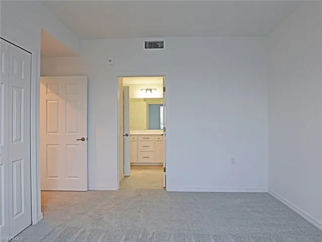 Unfurnished bedroom with light colored carpet, a closet, and connected bathroom