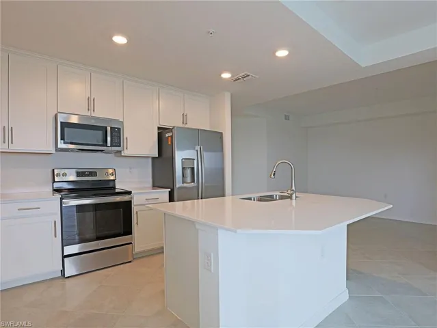 Kitchen with stainless steel appliances, recessed lighting, an island with sink, white cabinets, and light tile patterned flooring