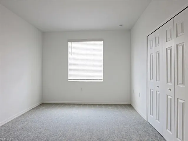 Unfurnished bedroom featuring light carpet and a closet
