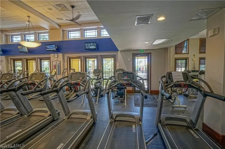 Exercise room with a towering ceiling, a drop ceiling, and ceiling fan