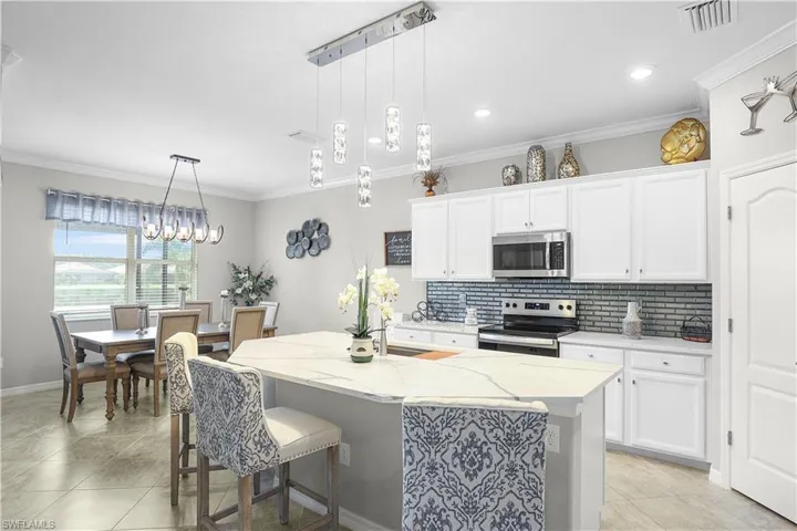 Kitchen with appliances with stainless steel finishes, decorative light fixtures, a kitchen breakfast bar, and light stone countertops