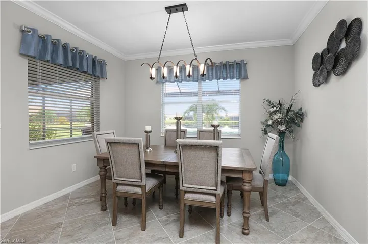 Tiled dining room with crown molding, an inviting chandelier, and a healthy amount of sunlight