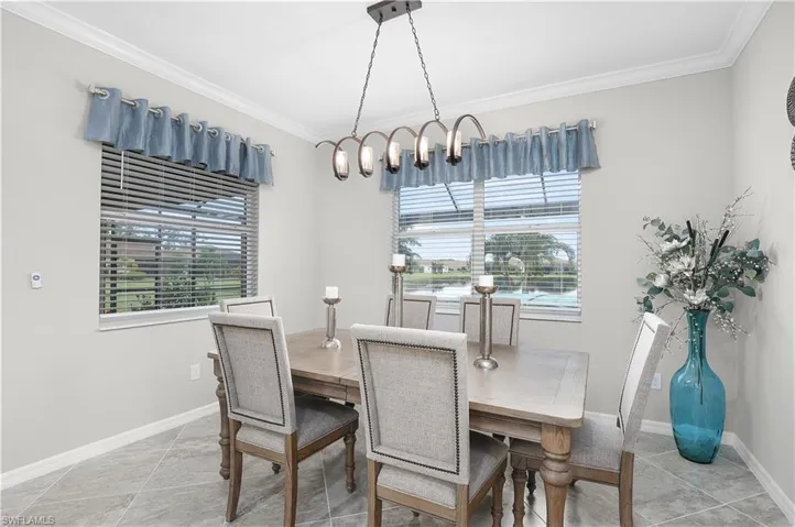 Dining area with light tile patterned flooring, ornamental molding, and a chandelier